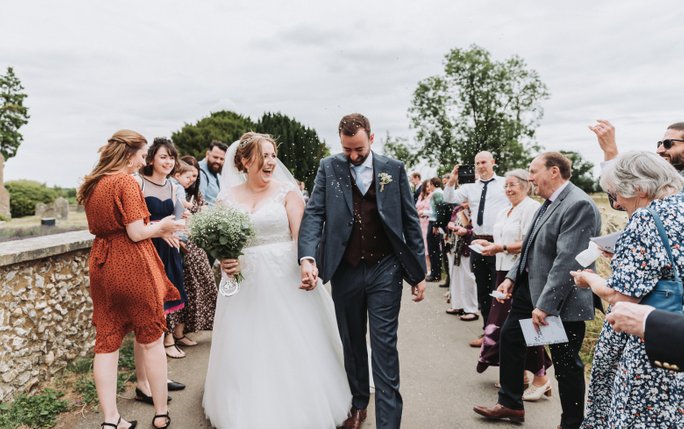 bride and groom walking through confetti on their wedding at Little Gaddensden church Wedding Photography