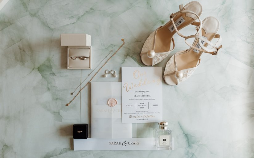 wedding flatlay wedding details of shoes, invitations, jewellery and rings