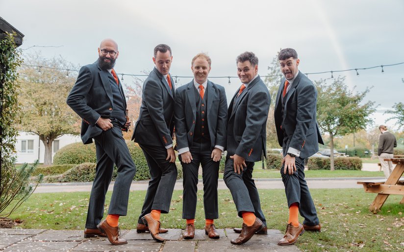 grooms showing off their matching socks on wedding day